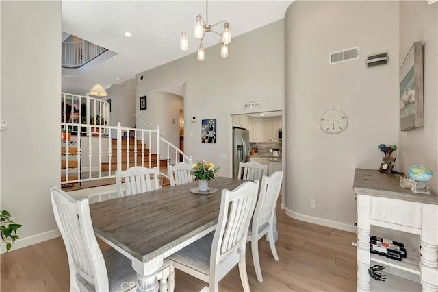 dining space with baseboards, light wood-style flooring, visible vents, and stairway