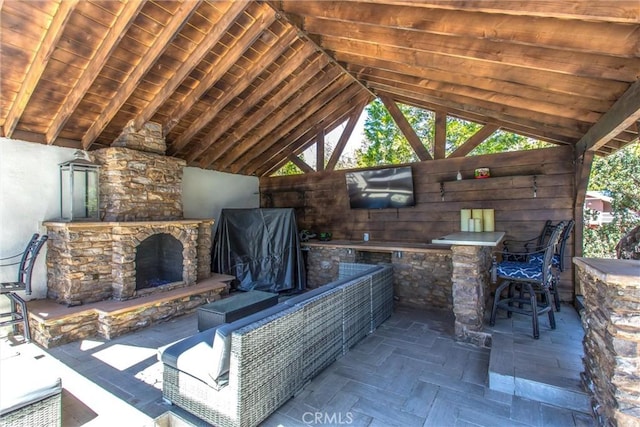 view of patio / terrace featuring a gazebo, an outdoor stone fireplace, and a bar