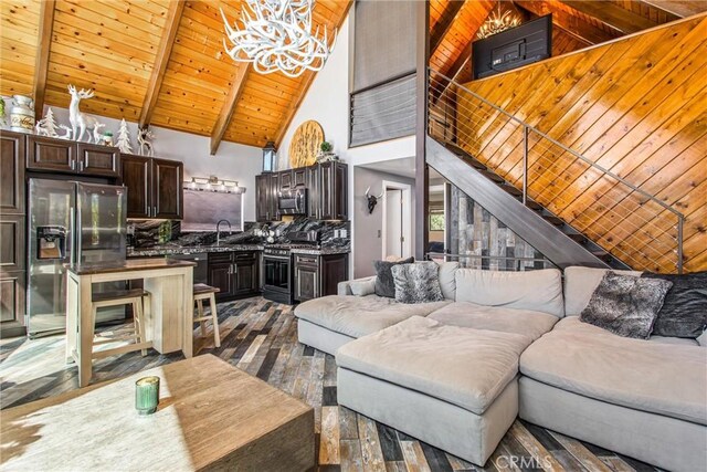 living area featuring dark wood-style flooring, an inviting chandelier, beamed ceiling, wooden ceiling, and high vaulted ceiling