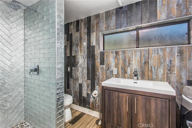 full bathroom with wood finished floors, vanity, a tile shower, toilet, and washer / clothes dryer