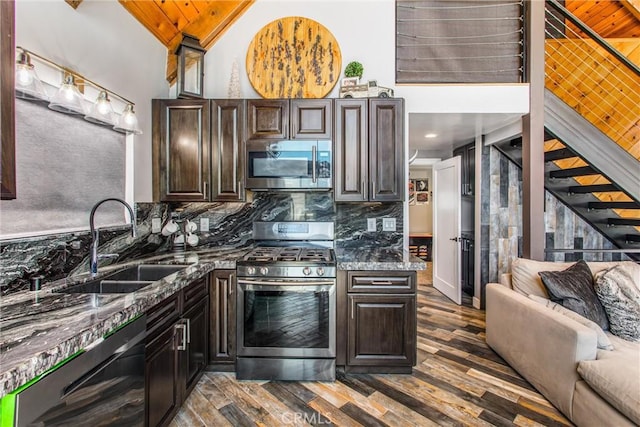 kitchen featuring dark wood finished floors, stainless steel appliances, a sink, decorative backsplash, and open floor plan