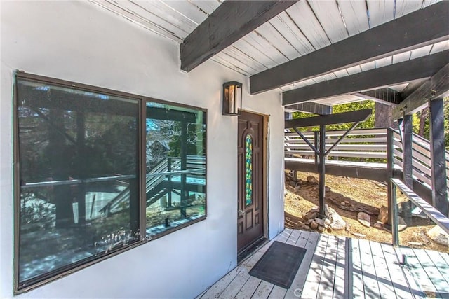 property entrance featuring a wooden deck and stucco siding