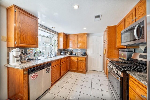 39240 Gunsmoke Ct, Palmdale, CA 93551 - kitchen with tasteful backsplash, stainless steel appliances, light tile patterned floors, brown cabinets, and visible vents
