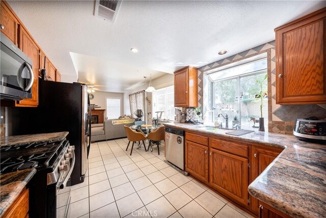 39240 Gunsmoke Ct, Palmdale, CA 93551 - kitchen featuring light tile patterned floors, tasteful backsplash, visible vents, stainless steel appliances, and brown cabinetry