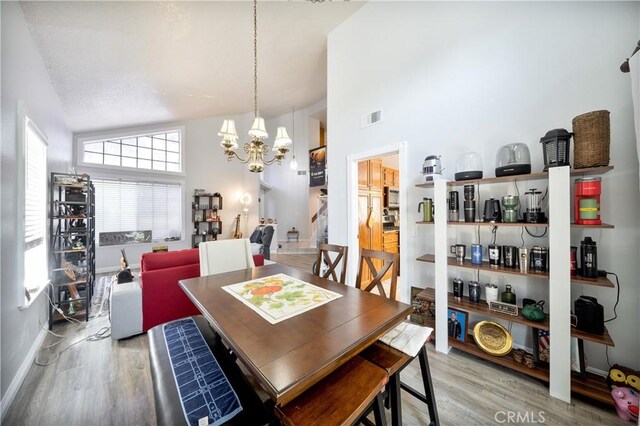 39240 Gunsmoke Ct, Palmdale, CA 93551 - dining area featuring wood finished floors, a chandelier, high vaulted ceiling, and visible vents