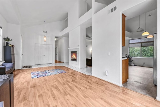 6845 Shubin Ln, Whittier, CA 90606 - unfurnished living room with a fireplace, light wood-style flooring, visible vents, and high vaulted ceiling