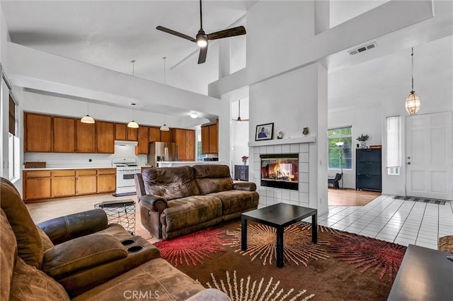 6845 Shubin Ln, Whittier, CA 90606 - living area featuring a tile fireplace, visible vents, light tile patterned flooring, high vaulted ceiling, and ceiling fan