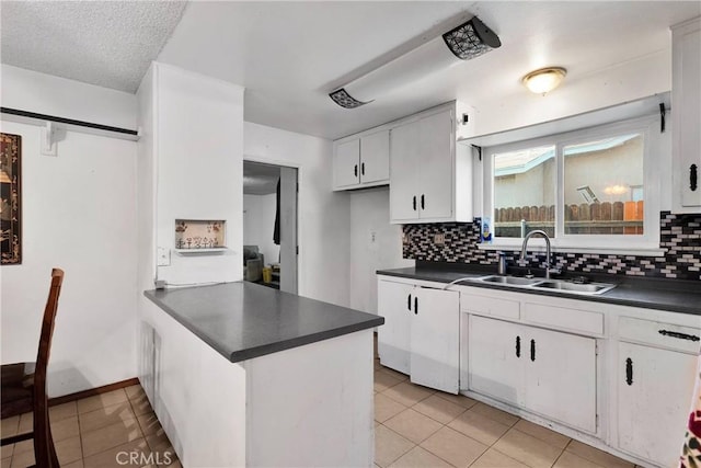 1844 Alston Ave, Colton, CA 92324 - kitchen featuring dark countertops, a peninsula, decorative backsplash, and white cabinets