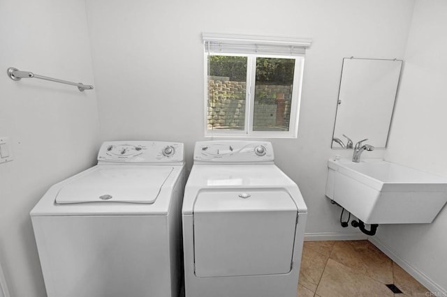 clothes washing area with a sink, light tile patterned floors, baseboards, laundry area, and independent washer and dryer