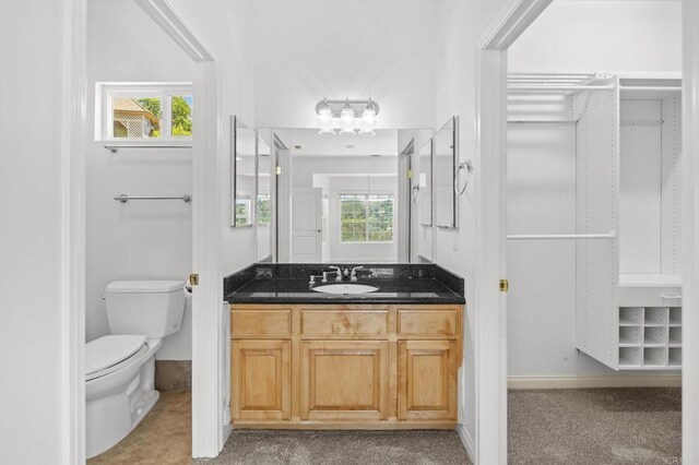 bathroom featuring a wealth of natural light, toilet, vanity, and baseboards