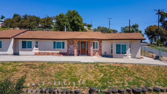 rear view of house with fence, brick siding, a lawn, a patio, and stucco siding
