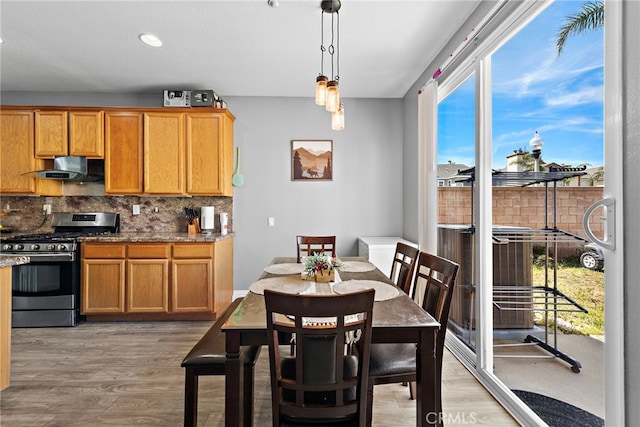 5332 Trailhawk Ave, Fontana, CA 92336 - kitchen with hanging light fixtures, stainless steel range with gas stovetop, light wood-style flooring, backsplash, and under cabinet range hood