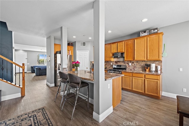 5332 Trailhawk Ave, Fontana, CA 92336 - kitchen featuring visible vents, stone countertops, under cabinet range hood, light wood finished floors, and appliances with stainless steel finishes