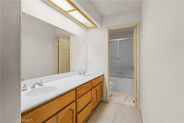 bathroom with double vanity, toilet, a sink, and tiled shower / bath