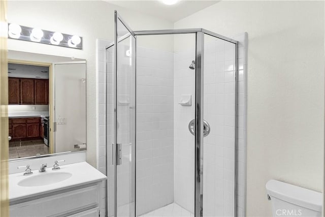 bathroom with toilet, a shower stall, and vanity