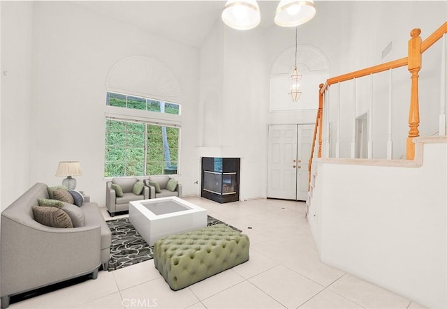 living area featuring tile patterned floors, visible vents, and a towering ceiling