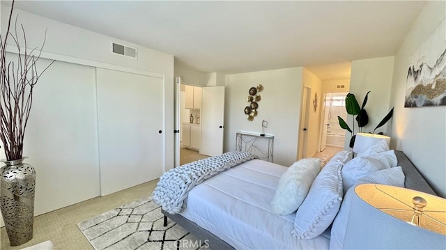 bedroom featuring a closet, visible vents, light carpet, and ensuite bathroom