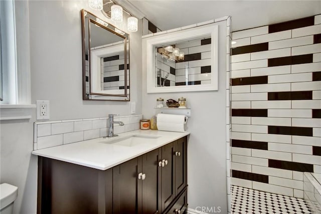 full bathroom featuring vanity, toilet, and a tile shower