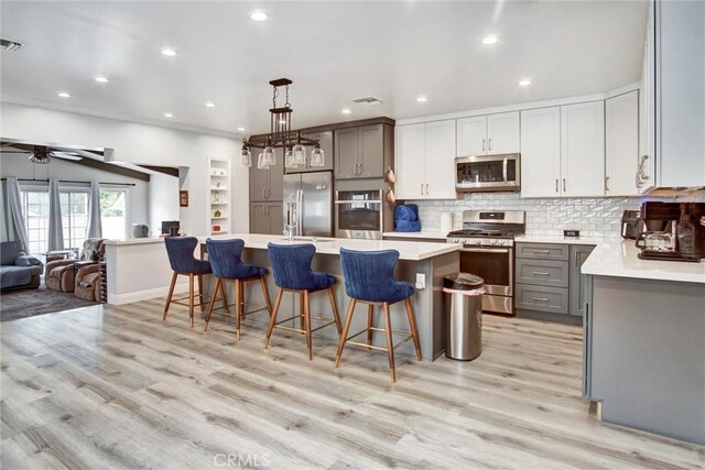 kitchen with appliances with stainless steel finishes, gray cabinetry, open floor plan, light countertops, and decorative backsplash