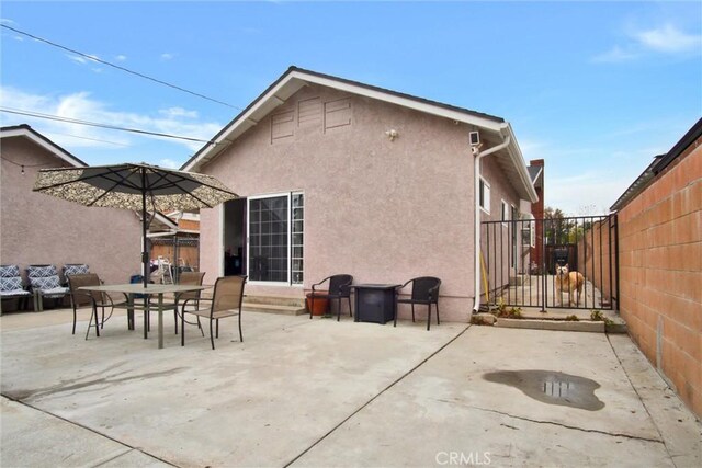 rear view of property featuring stucco siding, a fenced backyard, a patio area, and outdoor dining space
