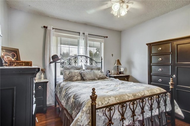 bedroom featuring dark wood-type flooring, a textured ceiling, and a ceiling fan