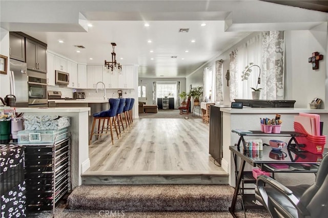 living area with a chandelier, recessed lighting, and light wood-style floors