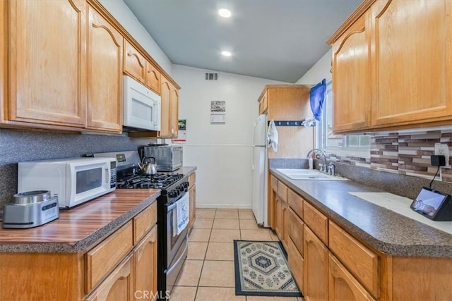 kitchen with dark countertops, visible vents, a sink, light tile patterned flooring, and white appliances