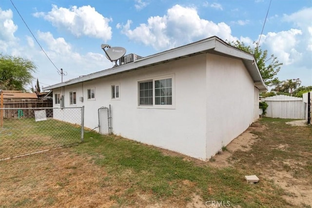 back of property with stucco siding, a lawn, and fence