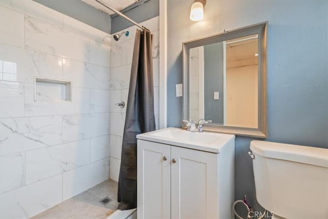 bathroom featuring toilet, vanity, and a tile shower