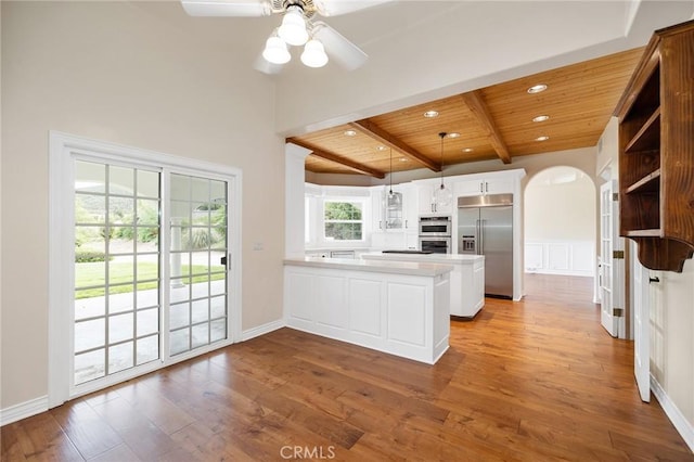 kitchen featuring wood finished floors, wood ceiling, arched walkways, stainless steel appliances, and a peninsula