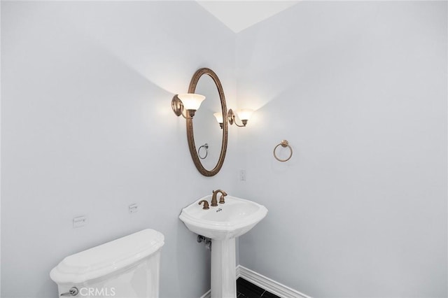 bathroom with toilet, baseboards, and a sink