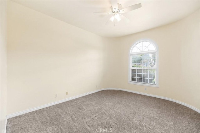 carpeted spare room featuring a ceiling fan and baseboards