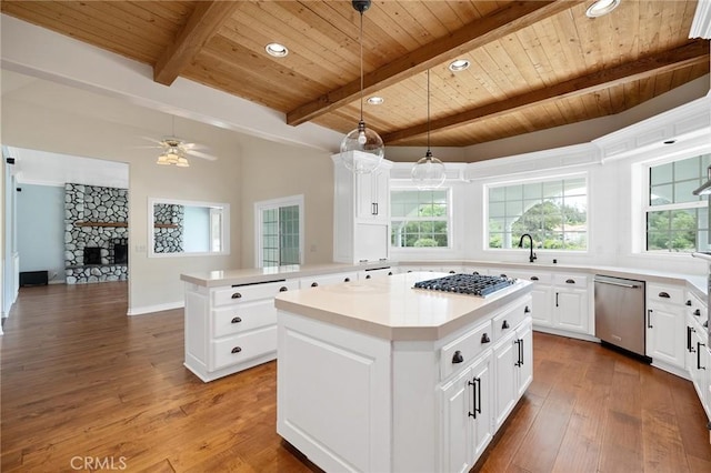 kitchen with stainless steel appliances, plenty of natural light, beamed ceiling, wooden ceiling, and a kitchen island