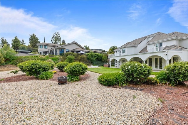 view of yard with a fire pit, french doors, and a balcony