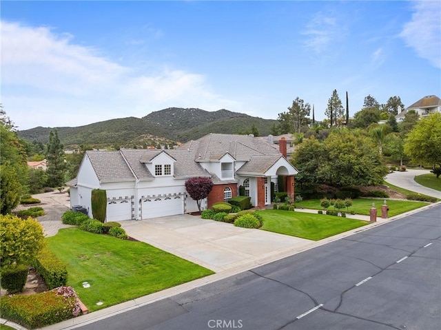 view of front of home featuring a chimney, stucco siding, driveway, a front yard, and a mountain view