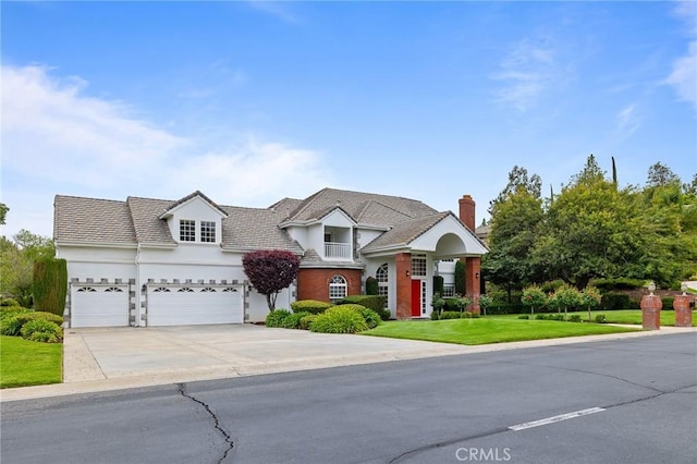 traditional-style house with a front lawn, driveway, a chimney, a garage, and stucco siding