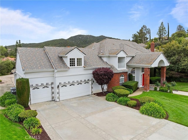 traditional-style house featuring central AC unit, driveway, a mountain view, a front yard, and stucco siding