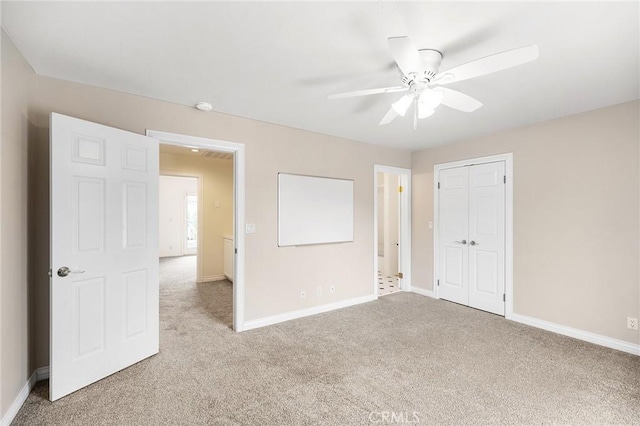 unfurnished bedroom with a closet, a ceiling fan, baseboards, and light carpet