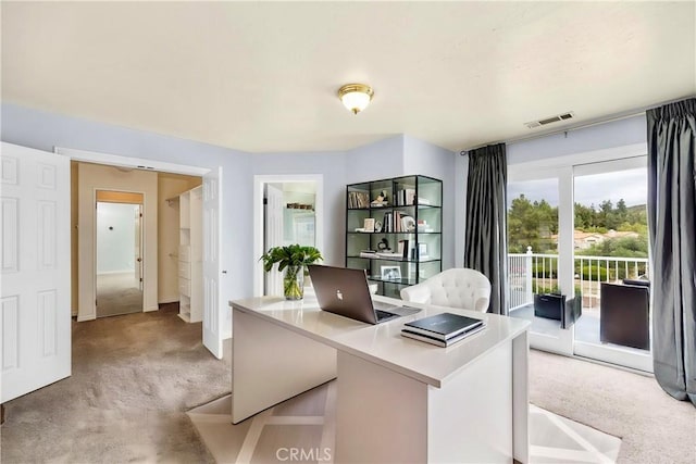office space with baseboards, visible vents, and light colored carpet