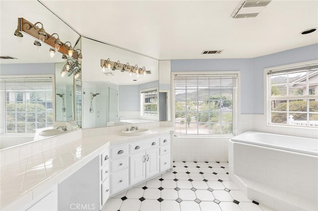 bathroom with visible vents, a garden tub, and vanity