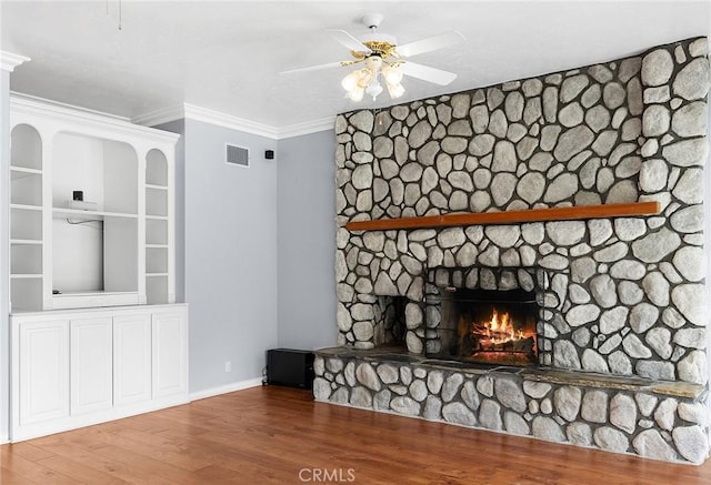 unfurnished living room featuring baseboards, visible vents, a ceiling fan, wood finished floors, and a stone fireplace