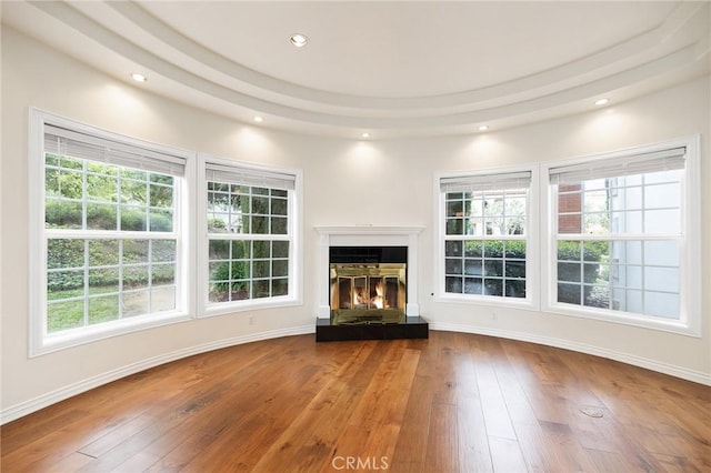 unfurnished living room with baseboards, a glass covered fireplace, recessed lighting, and wood-type flooring