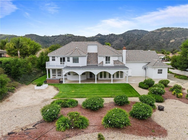 view of front facade with a porch, a front yard, a mountain view, and stucco siding