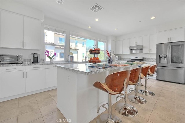 803 N Dalton Ave, Azusa, CA 91702 - kitchen with a toaster, under cabinet range hood, stainless steel appliances, visible vents, and light tile patterned floors