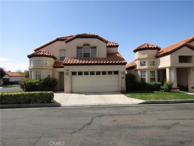 mediterranean / spanish-style house featuring driveway, a tiled roof, stucco siding, and a garage