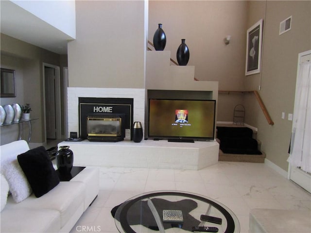 living area featuring visible vents, baseboards, marble finish floor, and a brick fireplace