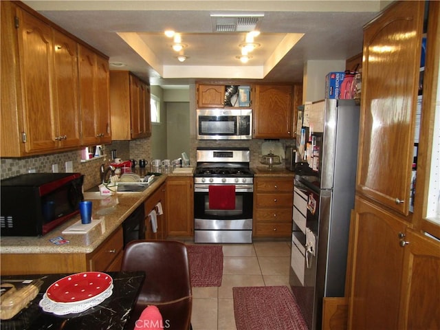 kitchen with visible vents, a sink, appliances with stainless steel finishes, and brown cabinets