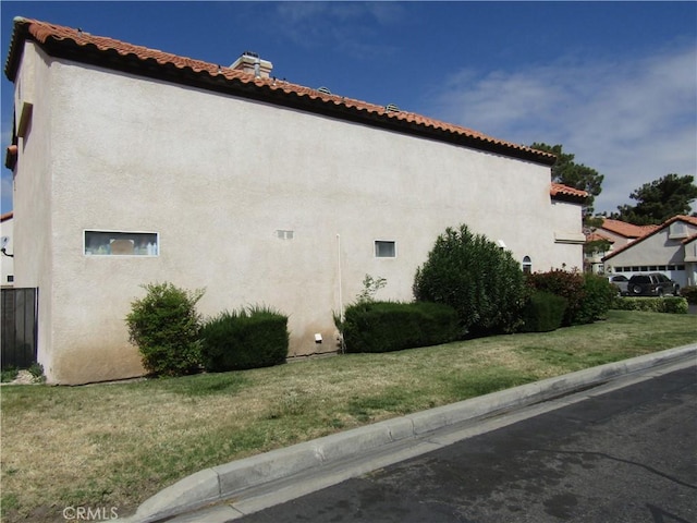 view of side of home with stucco siding and a yard