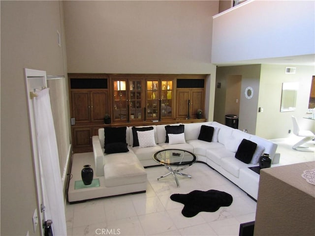 living area featuring a towering ceiling, visible vents, and marble finish floor