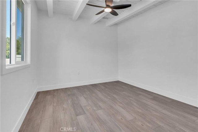 spare room with wood finished floors, beam ceiling, a ceiling fan, and baseboards